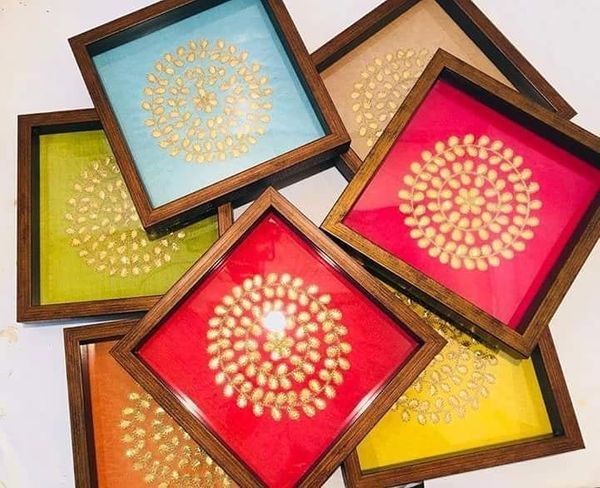 four colorful trays with gold designs on them sitting next to each other in front of a white wall