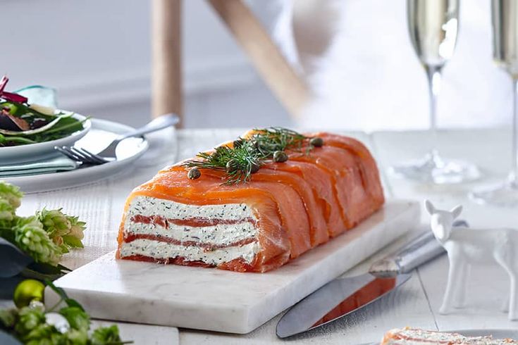 a large piece of salmon on a white platter next to two glasses of champagne