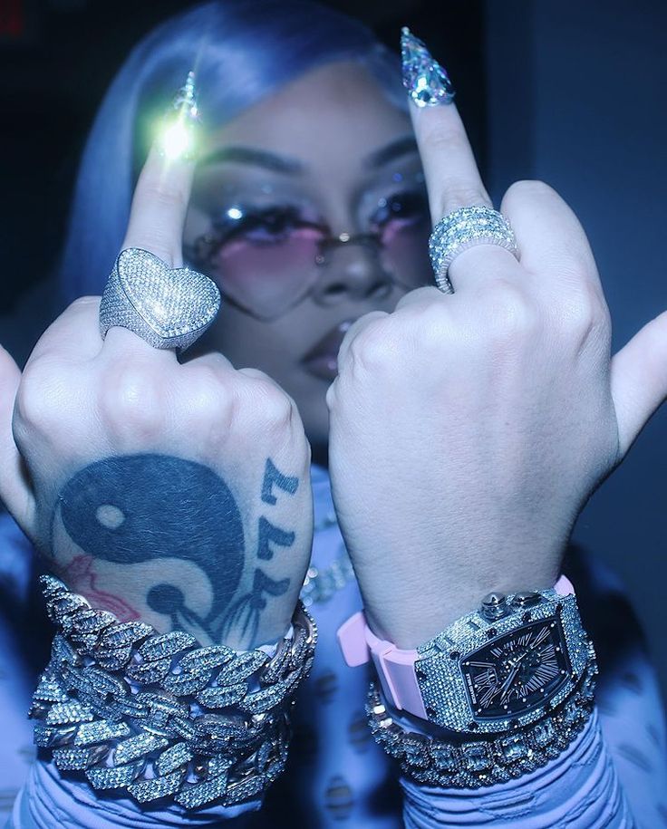 a woman with blue hair and tattoos holding her hands up in front of her face