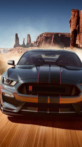 the new ford mustang is driving on a desert road with rocks in the background and an orange stripe down the front