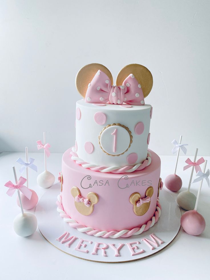 a pink and white cake with minnie mouse ears on top