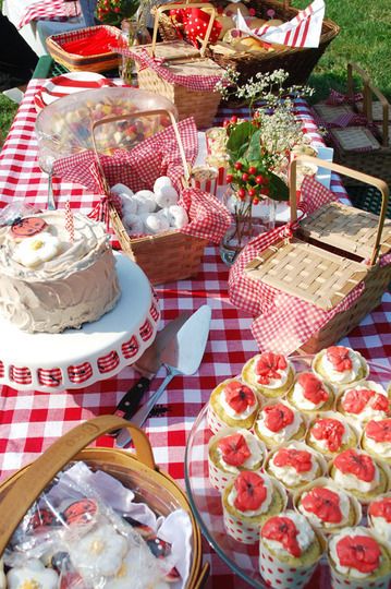 an outdoor picnic with food and desserts on the table, including cupcakes