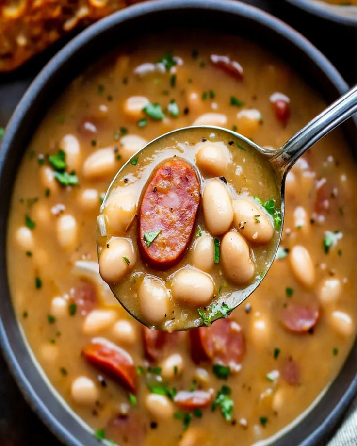 a spoon full of beans and sausage soup