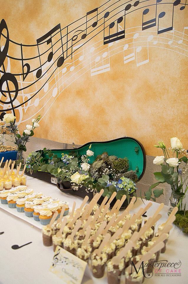 an arrangement of cupcakes and cake on a table with musical notes in the background