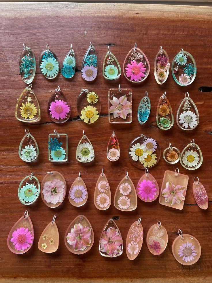 a table topped with lots of different types of earrings on top of wooden flooring