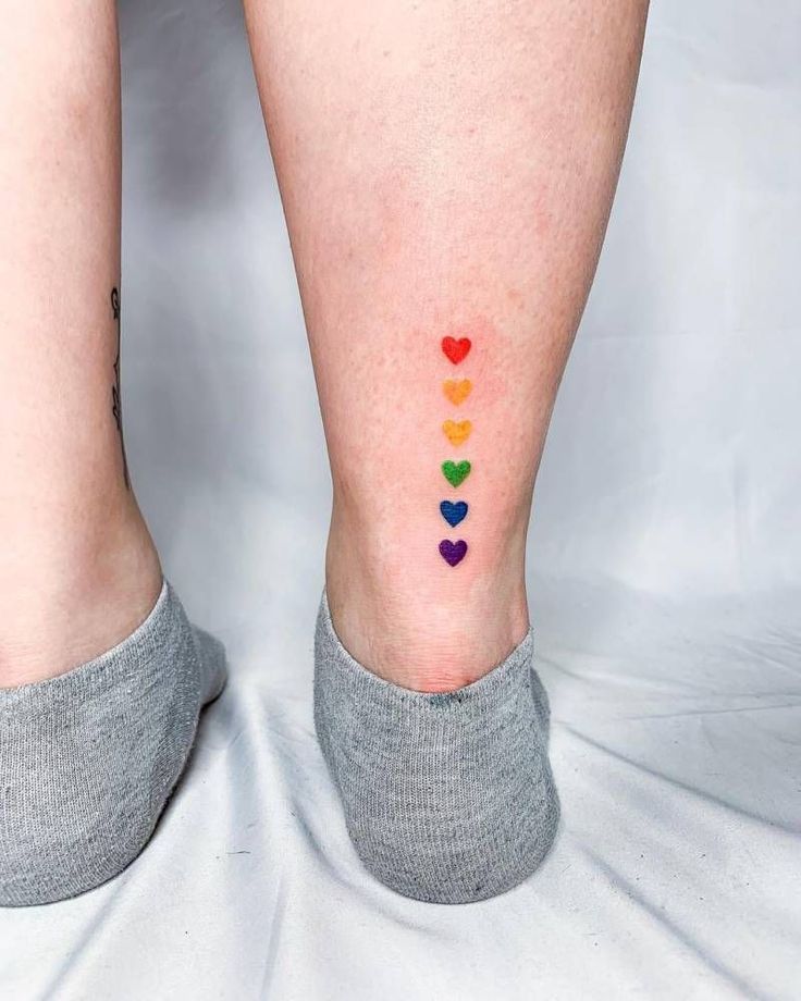 a woman's legs with colorful hearts painted on the bottom of her leg and ankle