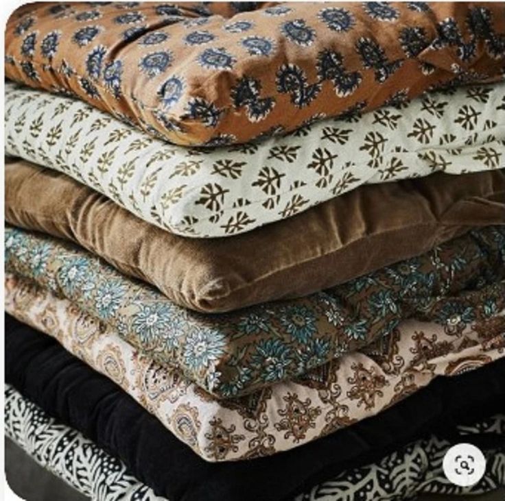 a pile of pillows stacked on top of each other in different colors and patterns,