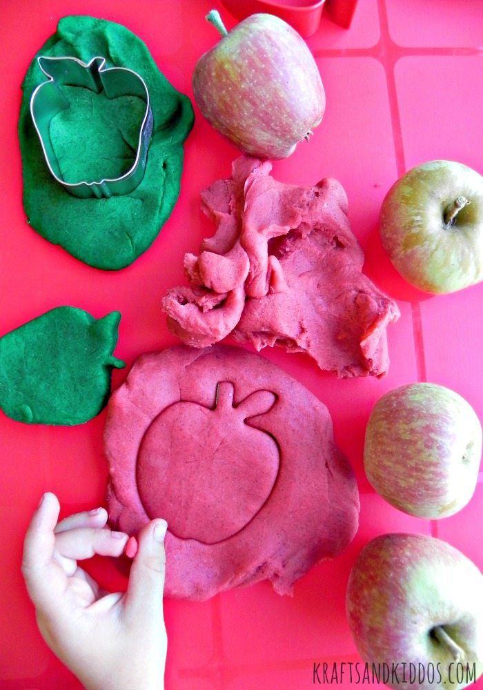 an apple and other food items on a pink surface with green apples in the background