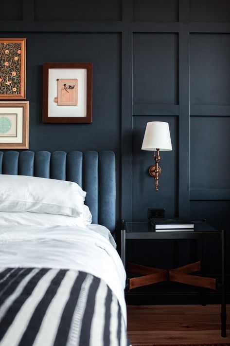 a bedroom with blue walls and white bedding, two framed pictures on the wall