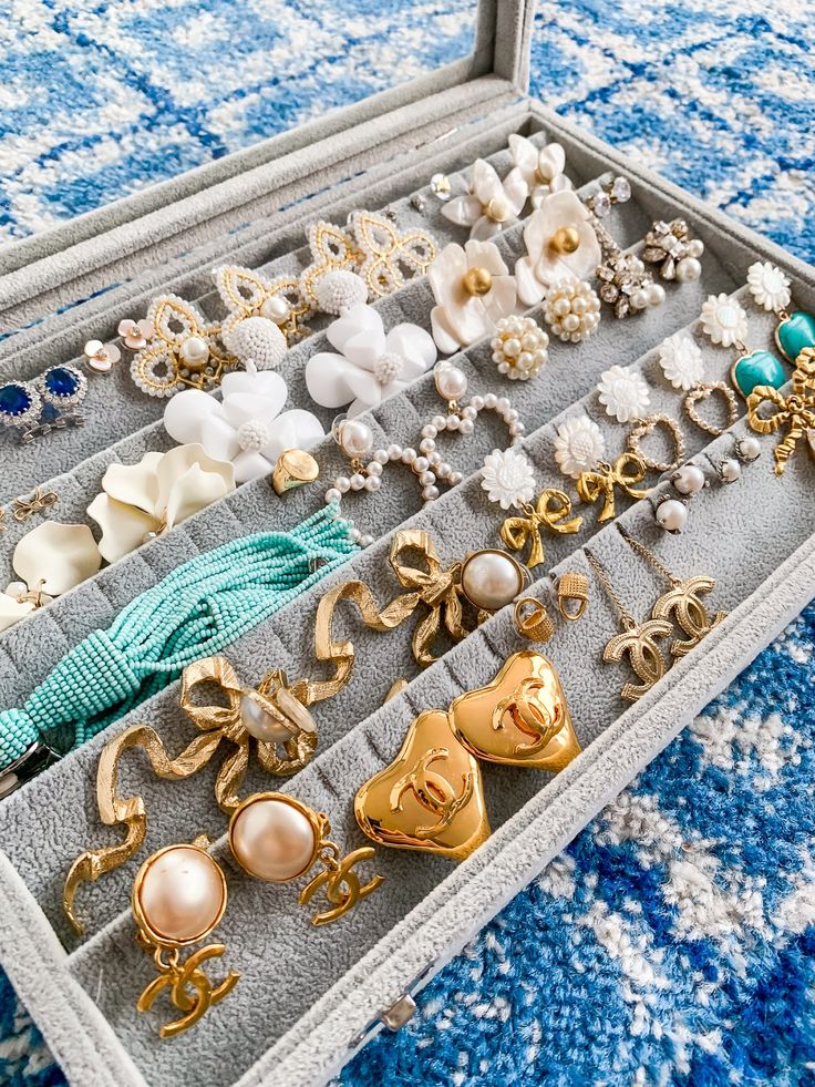 an open jewelry box with many different types of earrings and brooches in it