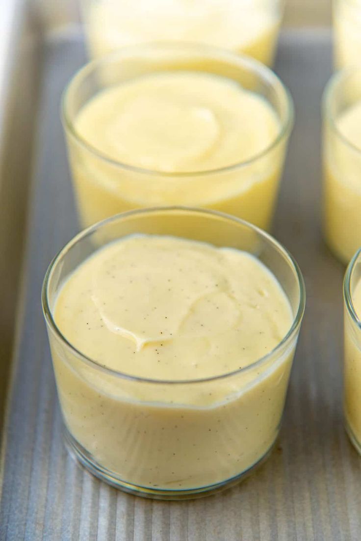 four glasses filled with yellow liquid sitting on top of a tray