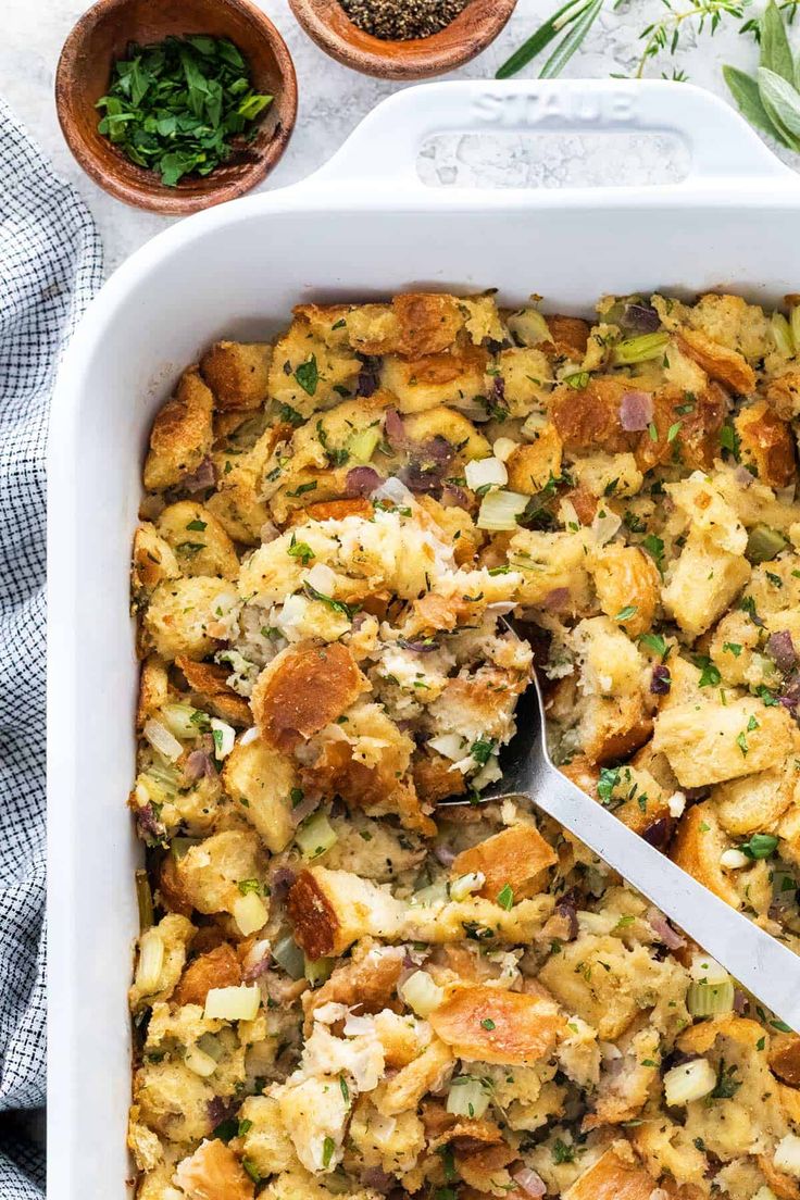 a casserole dish filled with stuffing and topped with a serving utensil