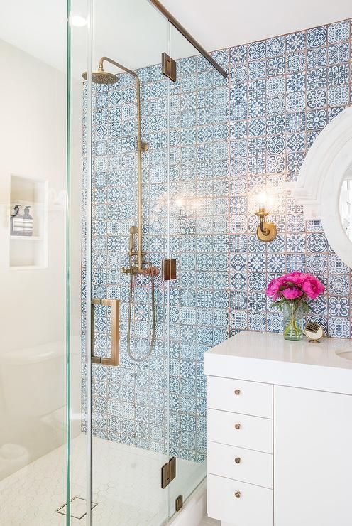 a bathroom with blue and white tile on the walls, shower head, sink, and mirror