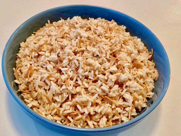 a blue bowl filled with rice on top of a table