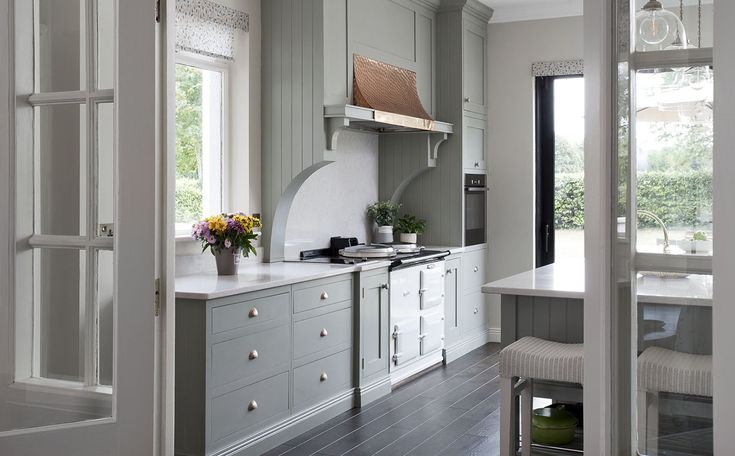 a kitchen with gray cabinets and white counter tops is seen through an open door to the dining room