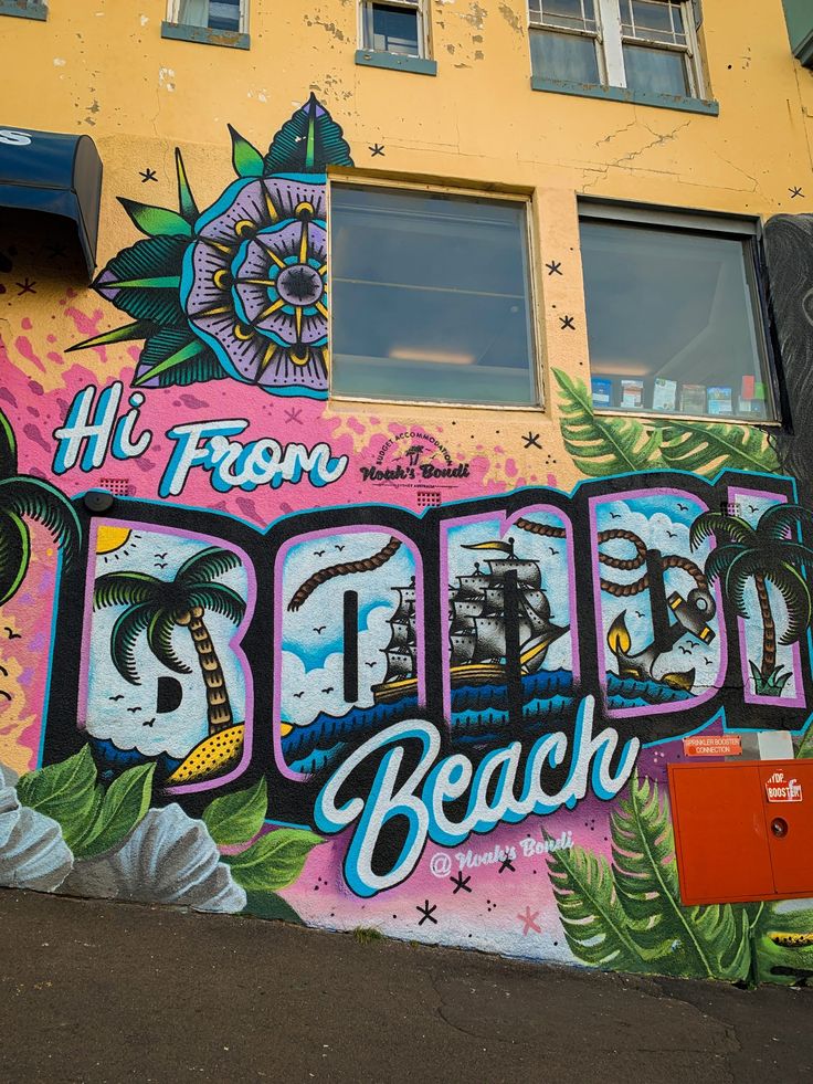 a colorful wall with the word beach painted on it's side in front of a yellow building