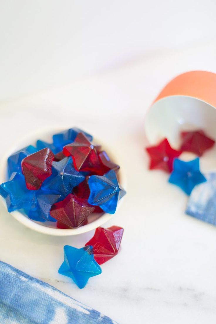 red, white and blue stars are in a bowl next to a cup on the table