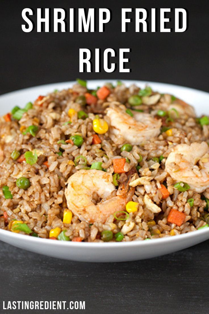 shrimp fried rice with peas and carrots in a white bowl on a black table