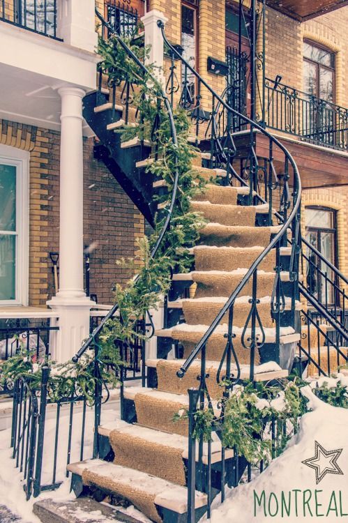 a set of stairs covered in snow next to a brick building with wrought iron railings