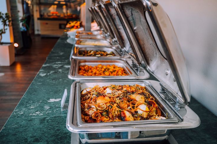 several trays of food are lined up on the counter