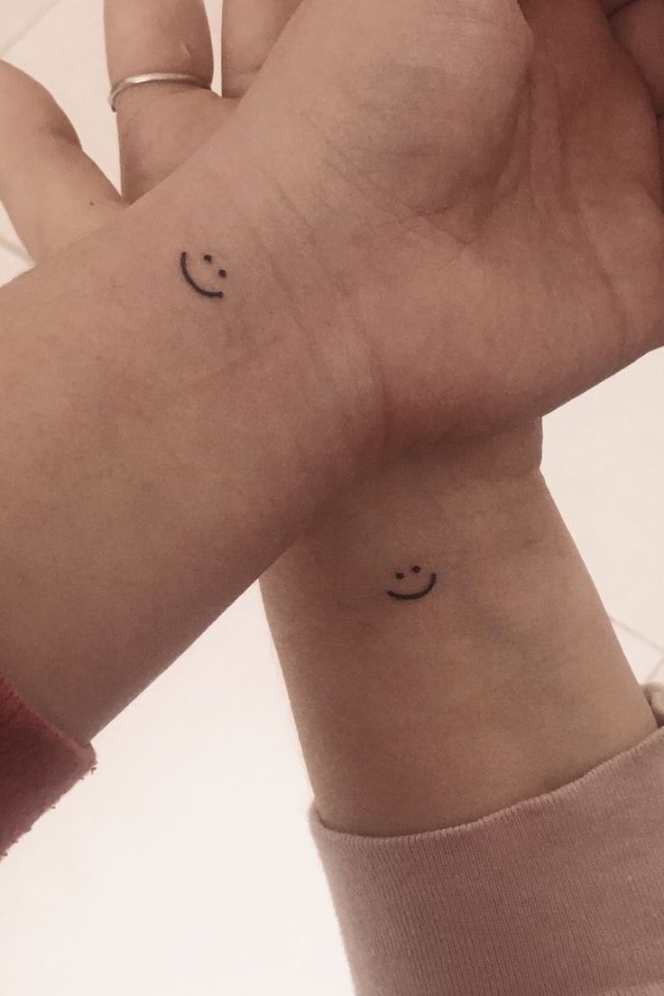 two wrist tattoos with smiley faces on them