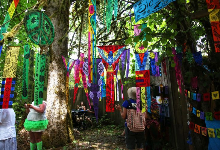 people are looking at colorful streamers hanging from trees