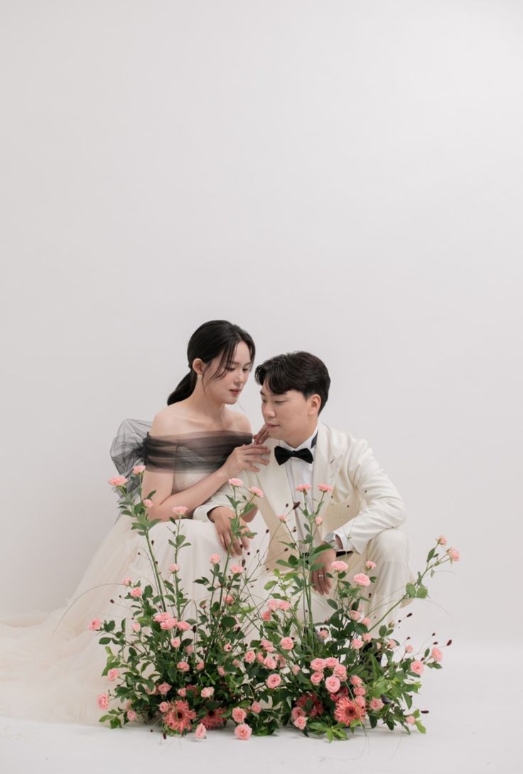 the bride and groom are sitting in front of flowers