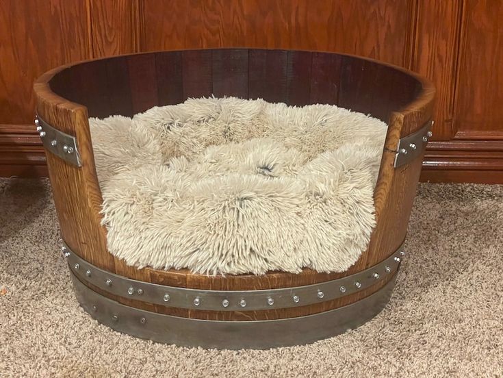 a dog bed made out of an old barrel with sheep fur in the middle and rivets on the sides