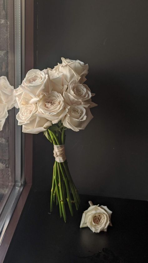 a bouquet of white roses sitting on top of a black table next to a window