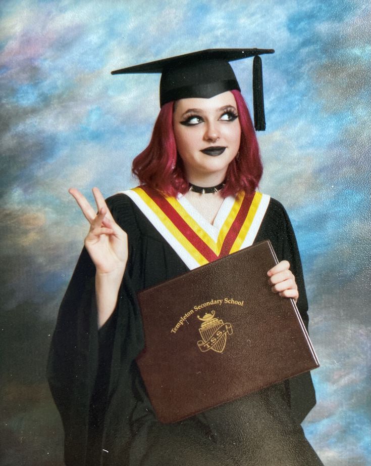 a woman with red hair wearing a graduation gown and holding a brown book in her hands