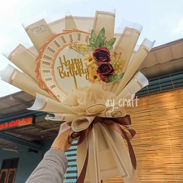 a person holding up a birthday card with flowers on it and the words happy birthday