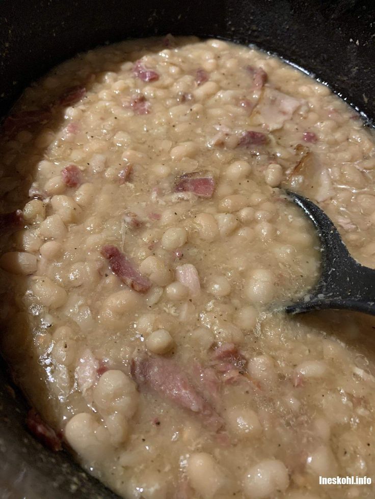 beans and ham cooking in a pot with a ladle