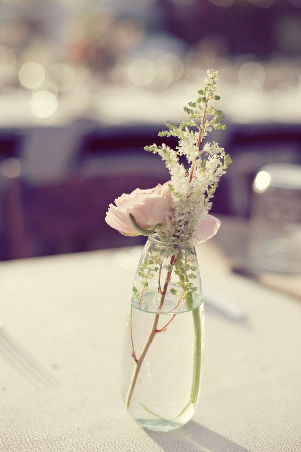 there is a vase with flowers in it sitting on the table top, ready to be used as a centerpiece