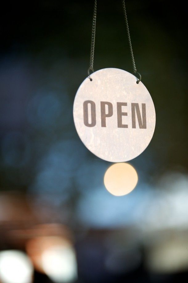 an open sign hanging from a chain