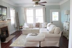 a living room filled with white furniture and a flat screen tv mounted on the wall