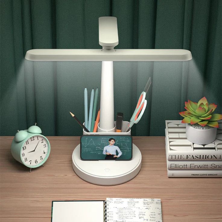 a desk with a clock, cell phone and various office supplies on top of it