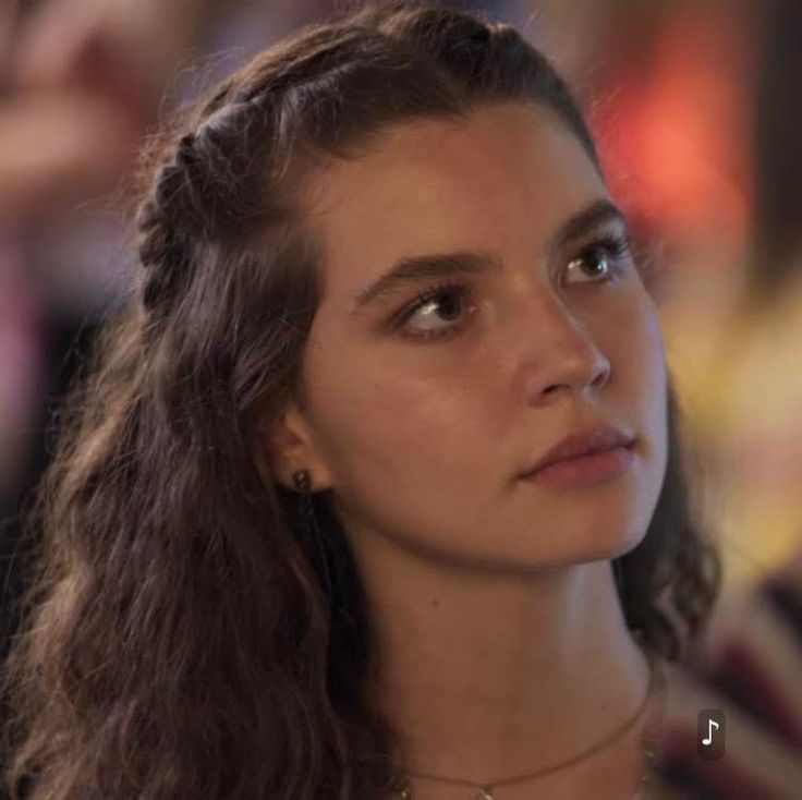 a close up of a person with long hair wearing a necklace and looking off to the side