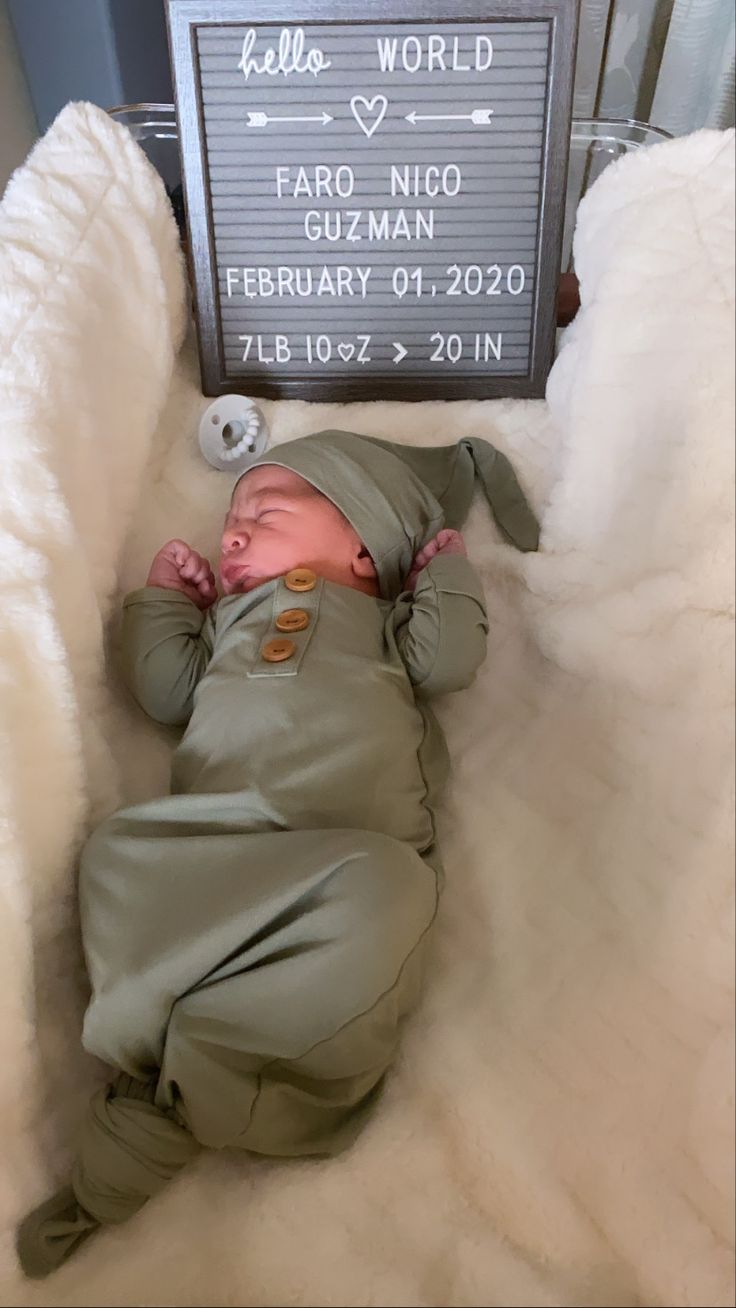 a baby is sleeping in a bed with a sign above it that says hello world