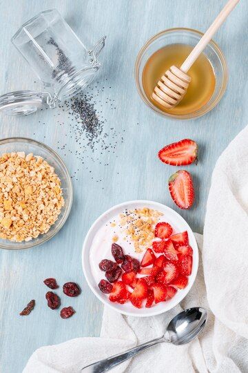 a bowl of granola, yogurt and strawberries on a blue table