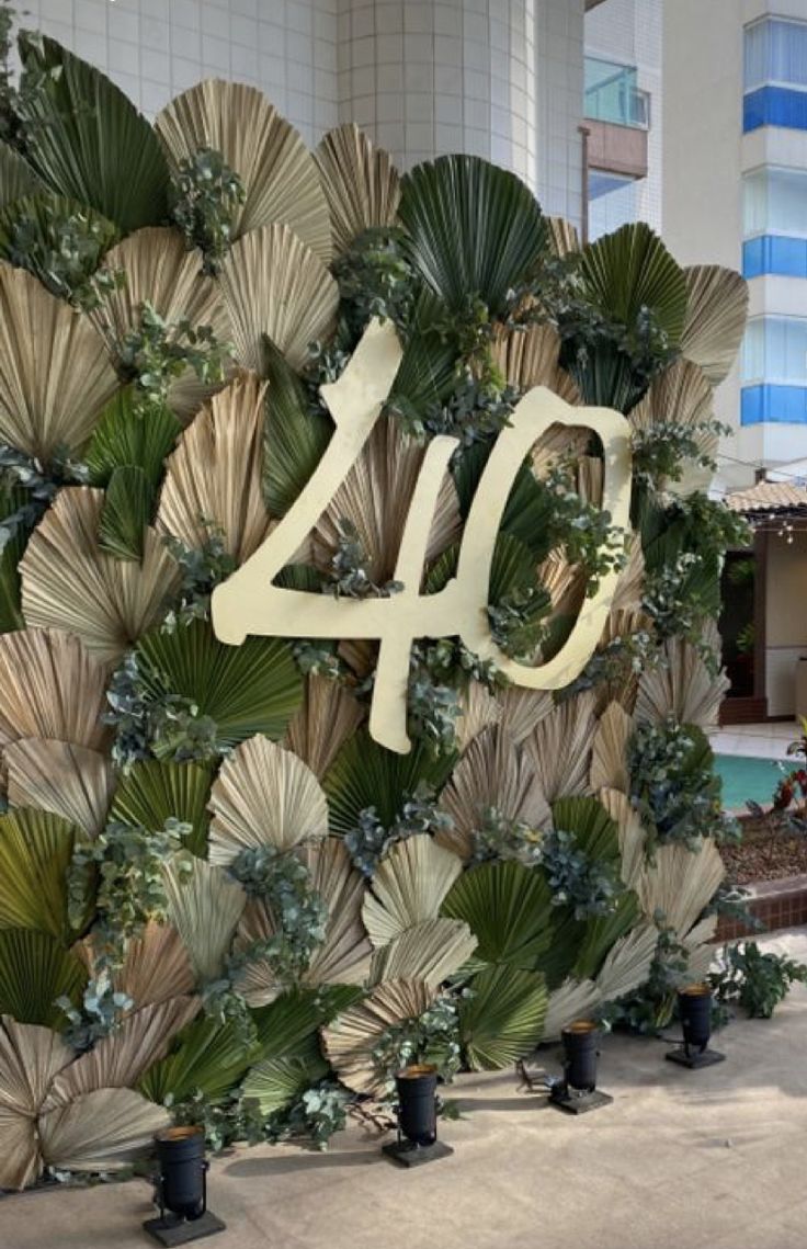 the number forty sign is displayed in front of a wall with palm leaves and greenery