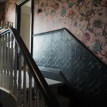 a stairway with floral wallpaper and metal handrails leading up to the second floor