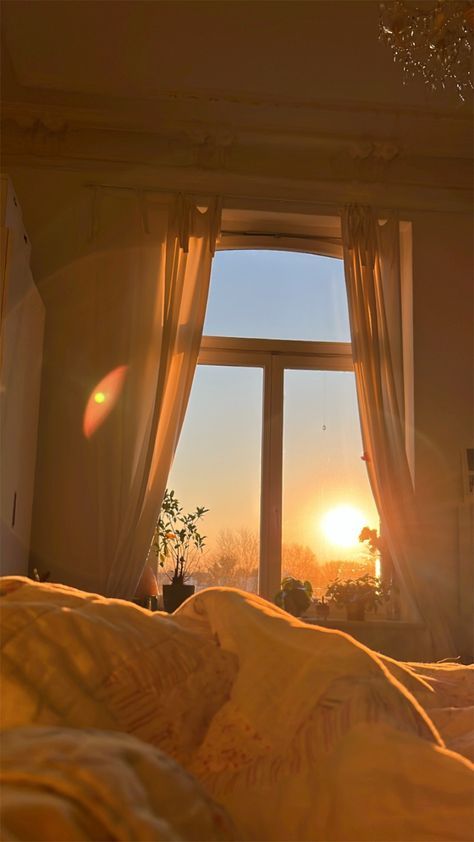 the sun is setting in front of an open window