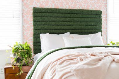 a green headboard in a bedroom with pink wallpaper and white bed linens