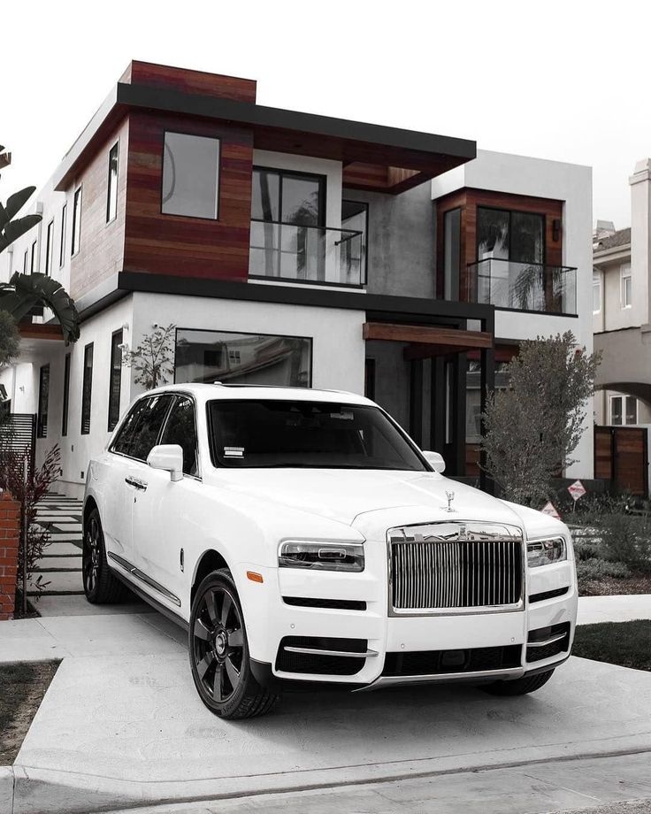 a white rolls royce parked in front of a house