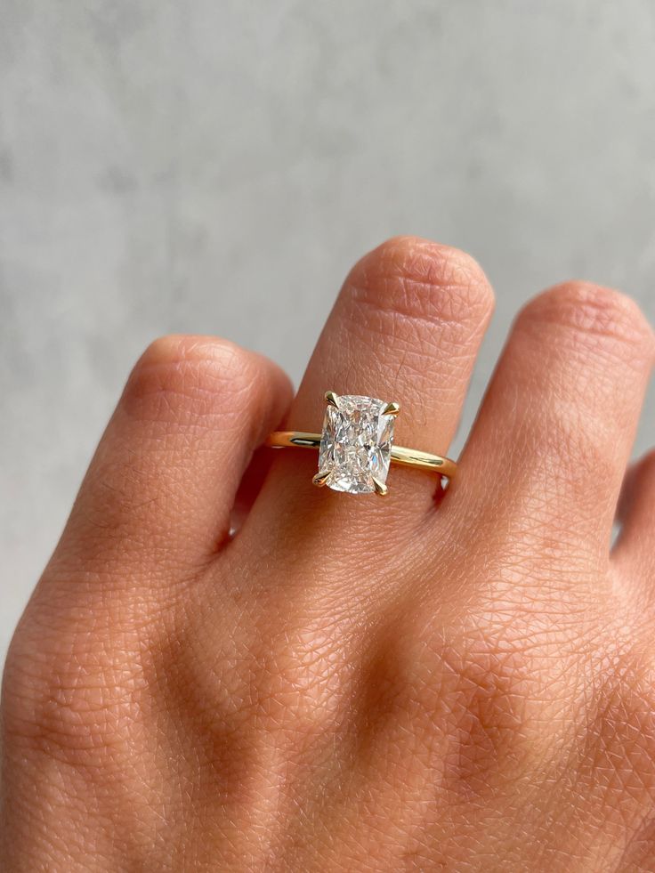 a woman's hand with a diamond ring on top of her finger, showing the center stone