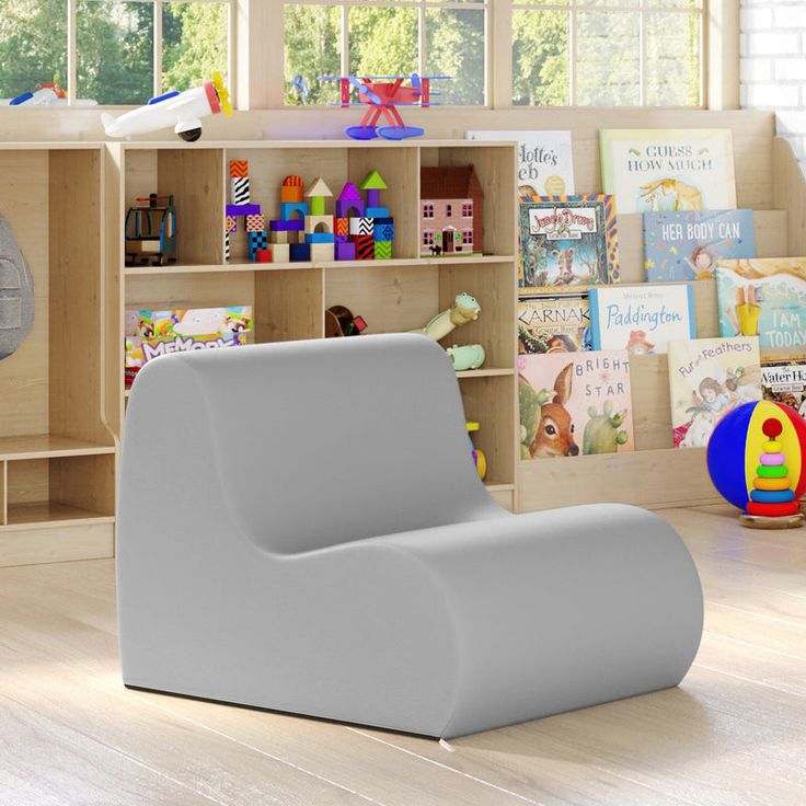 a child's room with toys and bookshelves in the corner, including a grey chair