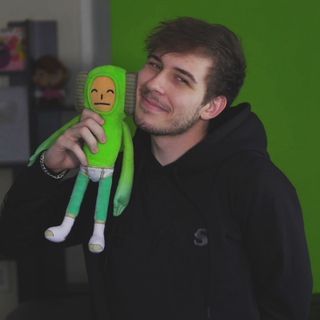 a man holding a green stuffed toy in his hand