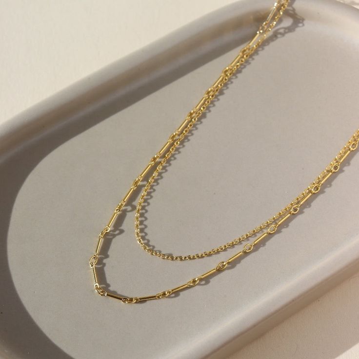 a 14k gold fill necklace made up of two chains, laid out on a sunny table Affordable Everyday Double Strand Chain Necklace, Minimalist Multi-strand Clavicle Chain Necklace, Everyday Multi-strand Double Chain Necklace, Modern Double Strand Necklace With Delicate Chain, Dainty Multi-strand Chain Necklace For Layering, Minimalist Multi-strand Layered Chain Necklace, Minimalist Multi-strand Chain Necklace, Modern Delicate Chain Layered Necklace, Multi-strand Paperclip Chain Necklace