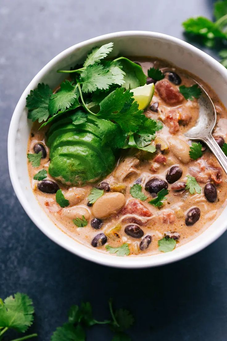 a white bowl filled with black beans, green peppers and cilantro on top of a table