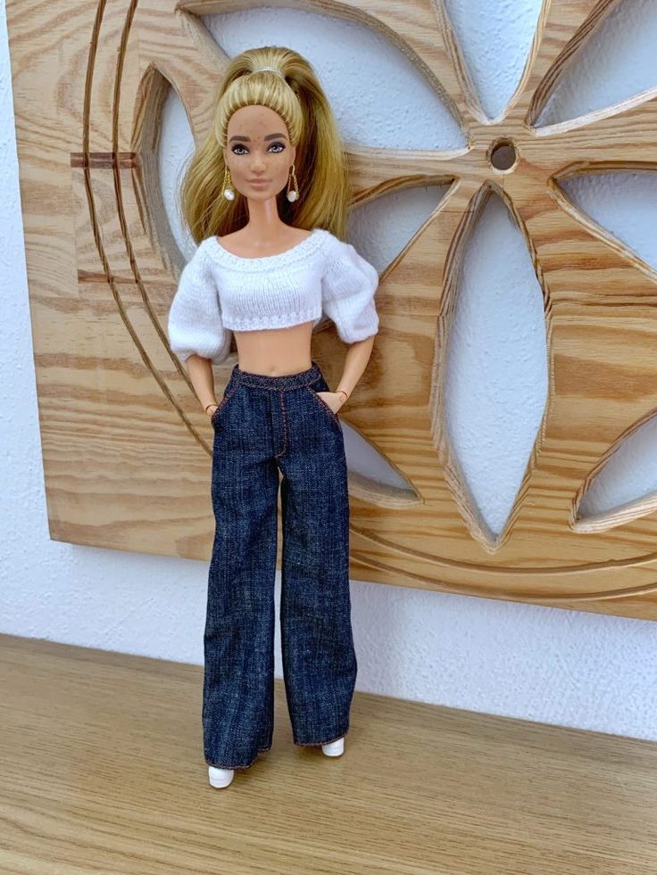 a barbie doll is standing in front of a wooden wall with a circular design on it